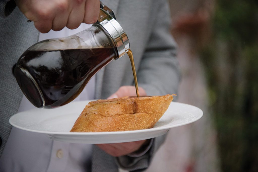 Person pouring syrup on french toast