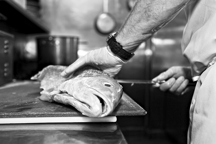 Phelps butchers an American red snapper; Photograph by Kim Longstreet