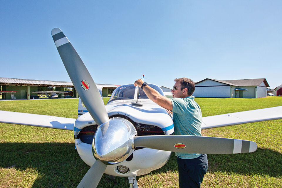 Jamie Clifford checks the oil level in his plane before take off. Photograph by Jeremiah Stanley