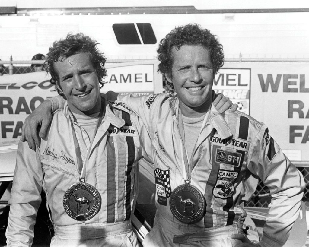 Haywood and Peter Gregg smile with their arms around each other. They are wearing large medals.