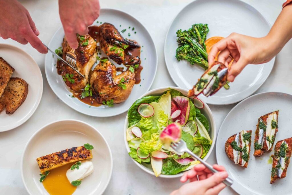 Six Foirette dishes with various hands sampling them. 