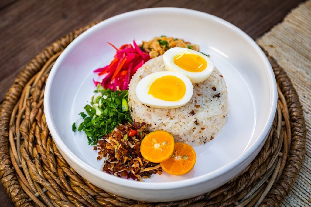 A dish with rice, garnishes and a hard boiled egg.